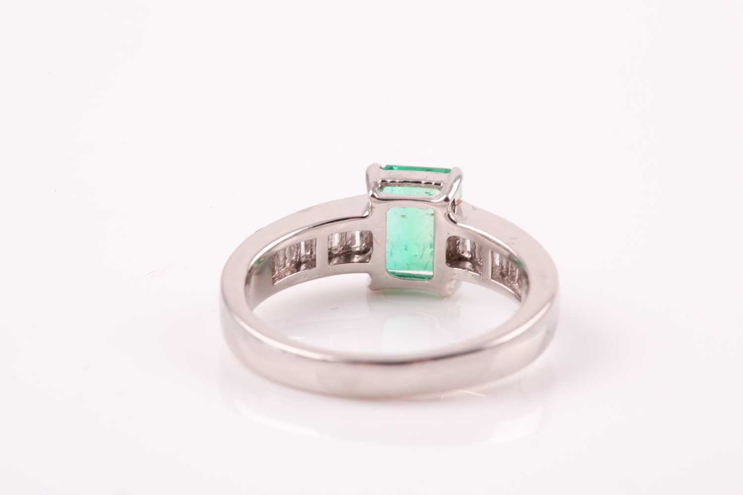 An emerald and diamond ring; the rectanguar, cut cornered, step cut emerald in four claw mount, to - Image 3 of 5