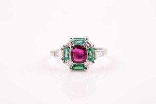 A ruby, emerald and diamond ring, the principal cushion-cut ruby in raised claw mount above a border