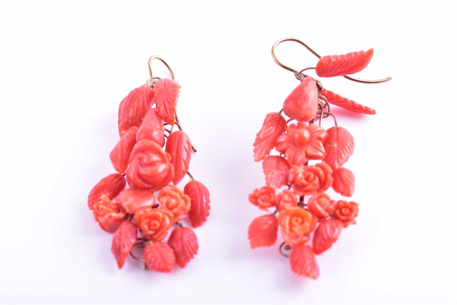 A pair of yellow metal and carved coral drop earrings, wire-set with foliate and floral carved red