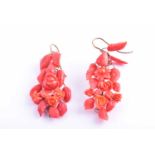 A pair of yellow metal and carved coral drop earrings, wire-set with foliate and floral carved red