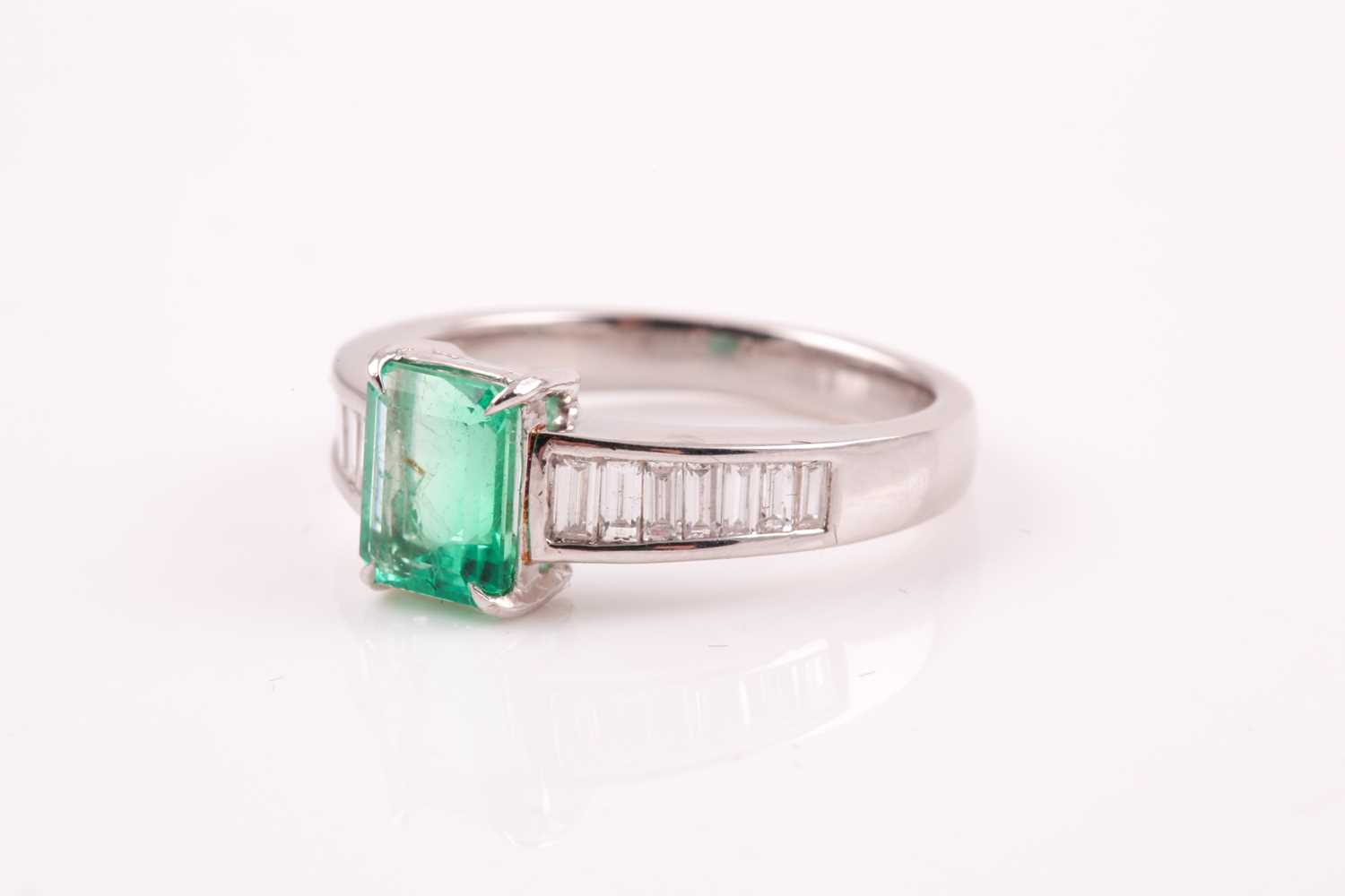 An emerald and diamond ring; the rectanguar, cut cornered, step cut emerald in four claw mount, to - Image 5 of 5