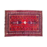 A 20th-century red ground tribal Afshar rug with central stepped lozenge and tree motif. Within