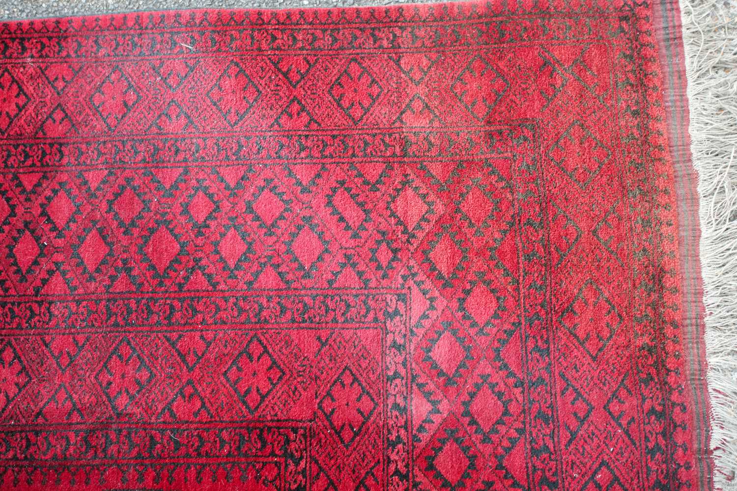 A 20th-century madder red ground Afghan carpet, with an open field of multi-point star-shaped - Image 3 of 4