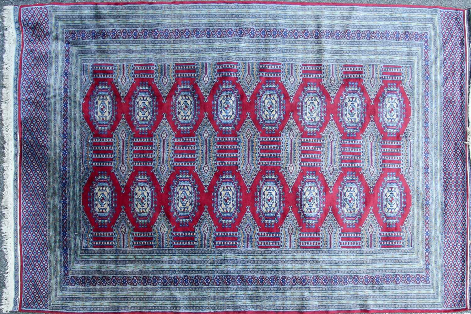 A 20th-century red ground Turkoman style carpet, with two rows of guls within multiple borders.