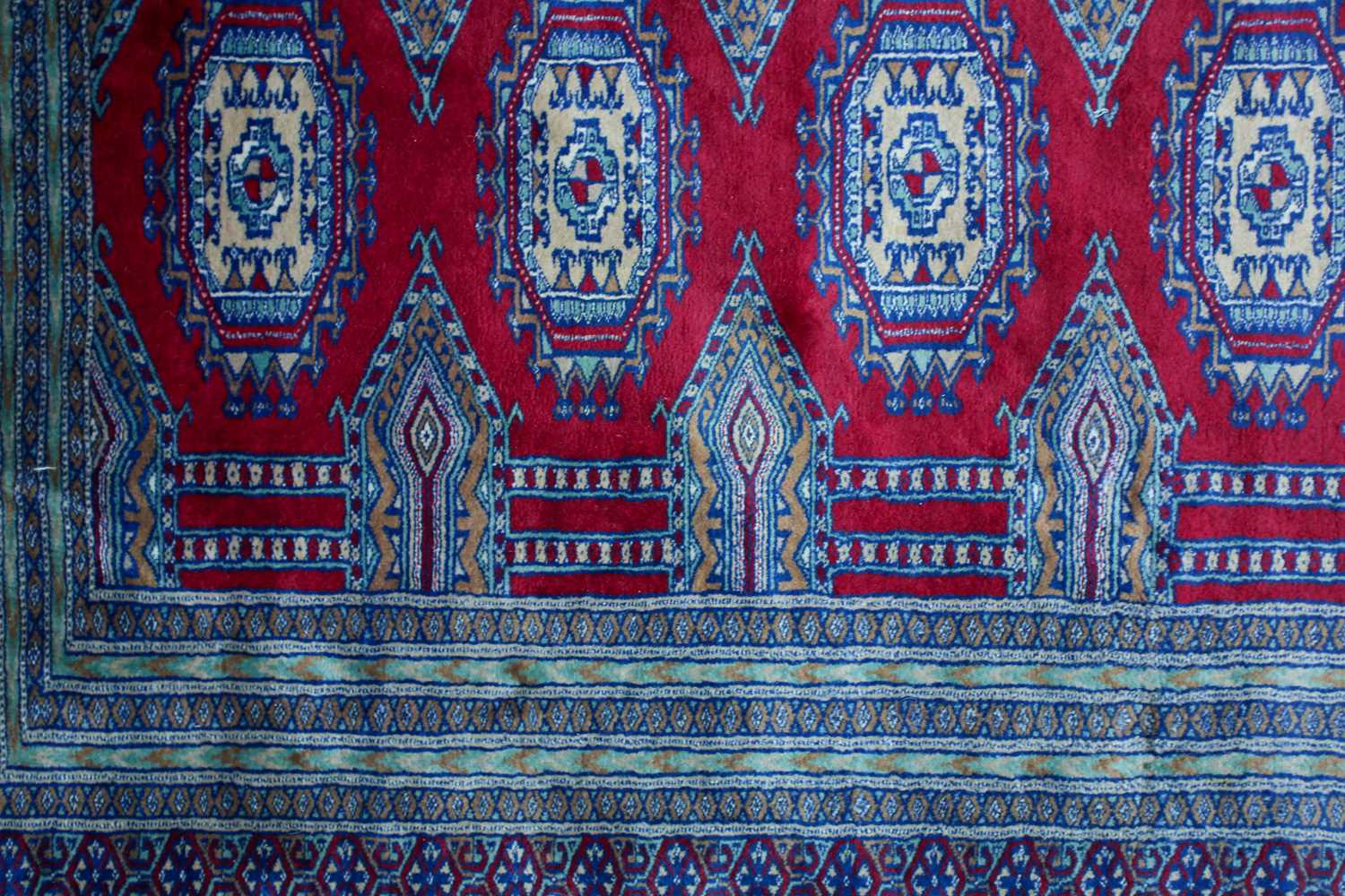 A 20th-century red ground Turkoman style carpet, with two rows of guls within multiple borders. - Image 3 of 3