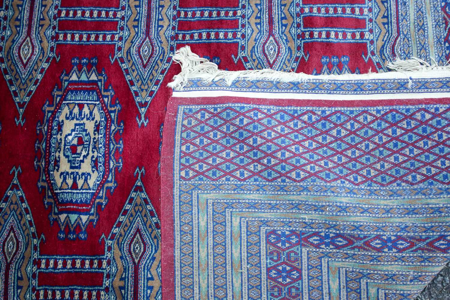 A 20th-century red ground Turkoman style carpet, with two rows of guls within multiple borders. - Image 2 of 3