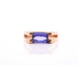 An 18ct yellow gold and tanzanite ring, set east to west with a rectangular mixed-cut tanzanite,