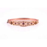 An Edwardian 9 carat rose gold, ruby, and diamond bangle; the centre gypsy set with graduated