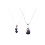 A white metal and sapphire pendant set with a pear-cut dark blue sapphire, on a silver chain,