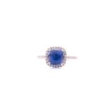 A sapphire and diamond cluster ring; the cushion cut sapphire in claw mount within an openwork
