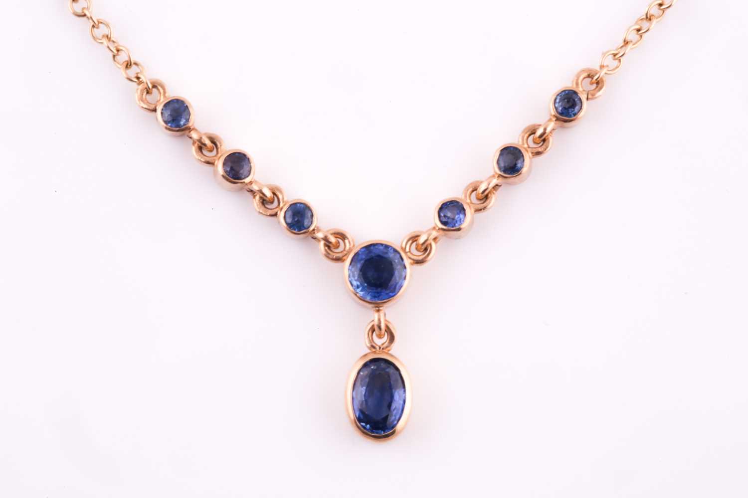 A 9ct yellow gold and blue sapphire drop pendant necklace, set with a mixed oval-cut sapphire