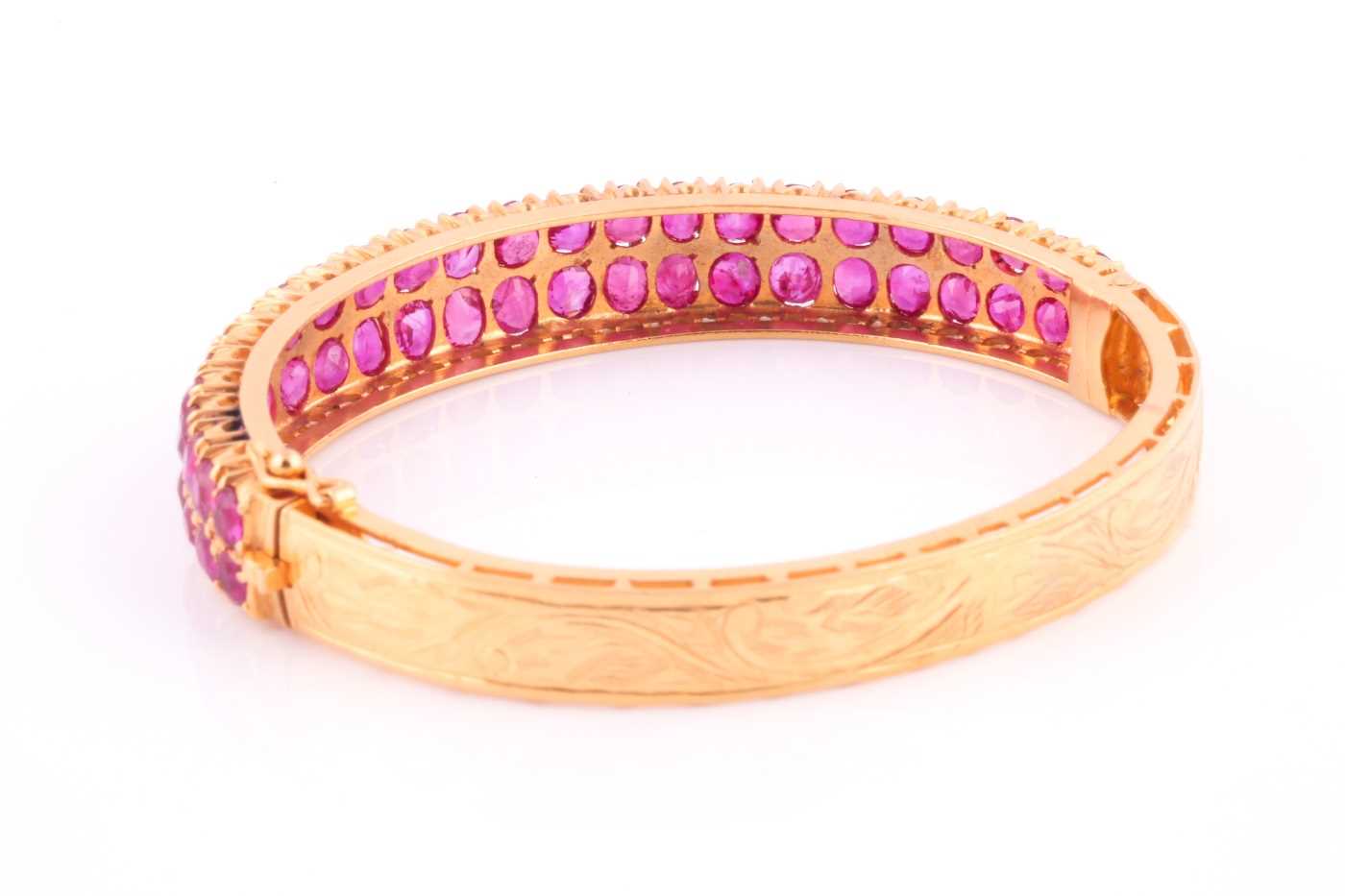 A ruby bangle; composed of two rows of mixed oval cut rubies in carved claw mounts to a foliate - Image 4 of 4