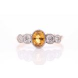 A yellow metal, diamond, and yellow sapphire ring, set with a mixed oval-cut sapphire flanked with