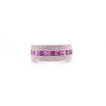 An 18ct white gold, diamond, and pink sapphire half eternity ring, the band centred with a calibre-
