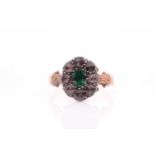A 19th century diamond and emerald ring, set with a mixed oval-cut emerald, within a border of mixed