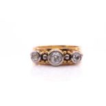 A yellow metal and diamond ring, collet-set in white gold with three round-cut diamonds of