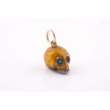 An unusual enamel skull pendant, the silver skull with yellow enamel decoration, with green gemstone