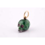 A silver and green enamel skull pendant, having round-cut ruby eyes, the suspension loop marked 750,