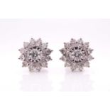 A pair of 18ct white gold and diamond cluster earrings, the starburst mounts centred with a round