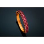 A ruby bangle; composed of two rows of mixed oval cut rubies in carved claw mounts to a foliate