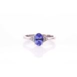 A 9ct white gold, diamond, and tanzanite ring, set with a mixed oval-cut tanzanite, with three small