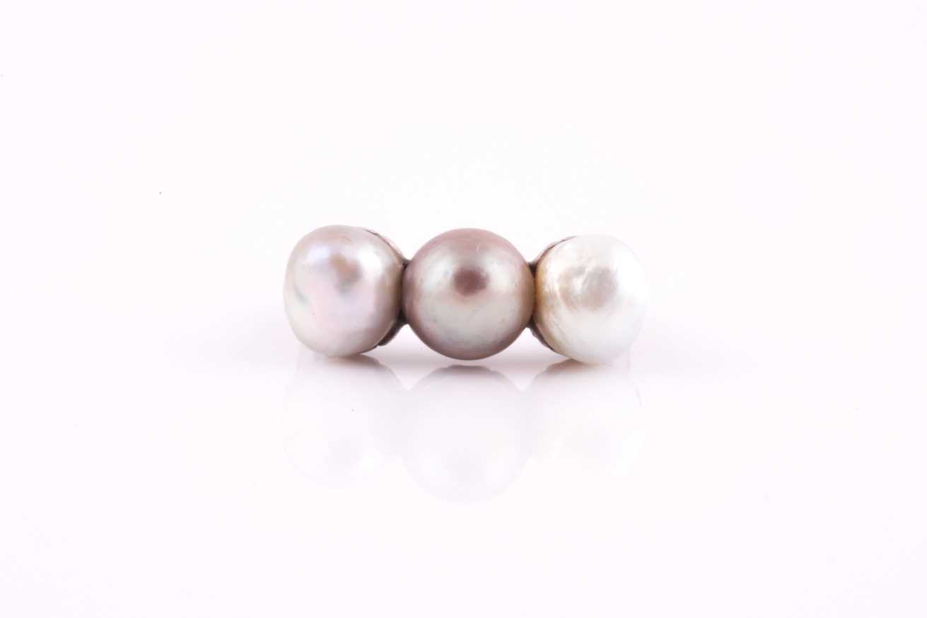 A pearl and diamond ring, set with three natural saltwater pearls, white, pale, and darker grey, the