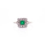 A platinum, diamond, and emerald ring, set with a square-cut emerald within a border of round-cut