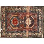 A small 20th-century red ground Kazak rug with a central geometric design within stylized "wine