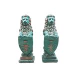 A pair of large green-painted stone lions, each behind an armorial shield, on a stepped square base,