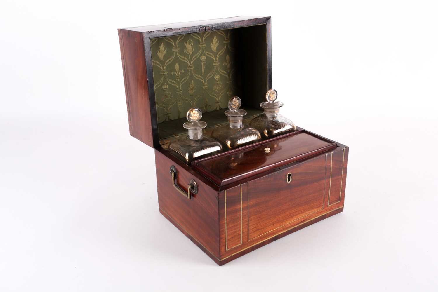 A Regency mahogany and brass bound three-bottle decanter set, the silk-lined interior with bottle