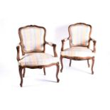 A pair of Louis XV style walnut fauteuils, With carved cresting, channel moulded frames and stuff