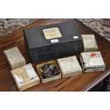 A leather box of musical instrument fittings, including reeds, violin strings, violin rosewood pegs,