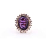 A yellow metal, diamond, and amethyst cocktail ring, set with a large mixed oval-cut amethyst,