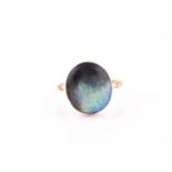 A yellow metal and boulder opal ring, the rounded oval stone in a closed-back setting, with shaped