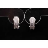 A pair of white metal and diamond half hoop earrings, set with a central row of baguette-cut