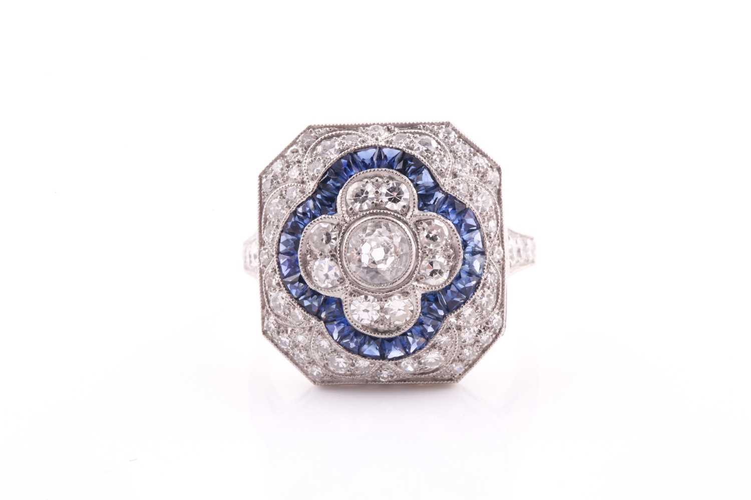 A platinum, diamond, and sapphire cocktail ring, set with a central quatrefoil floral design, within