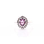 A platinum, diamond, and pink sapphire ring, set with a mixed oval-cut pink sapphire of