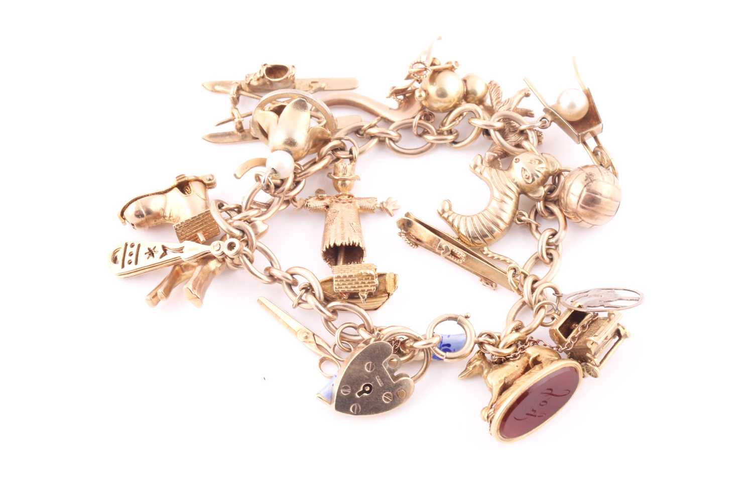 A yellow metal charm bracelet, the heart shaped padlock clasp hall marked 9 ct gold, with twenty