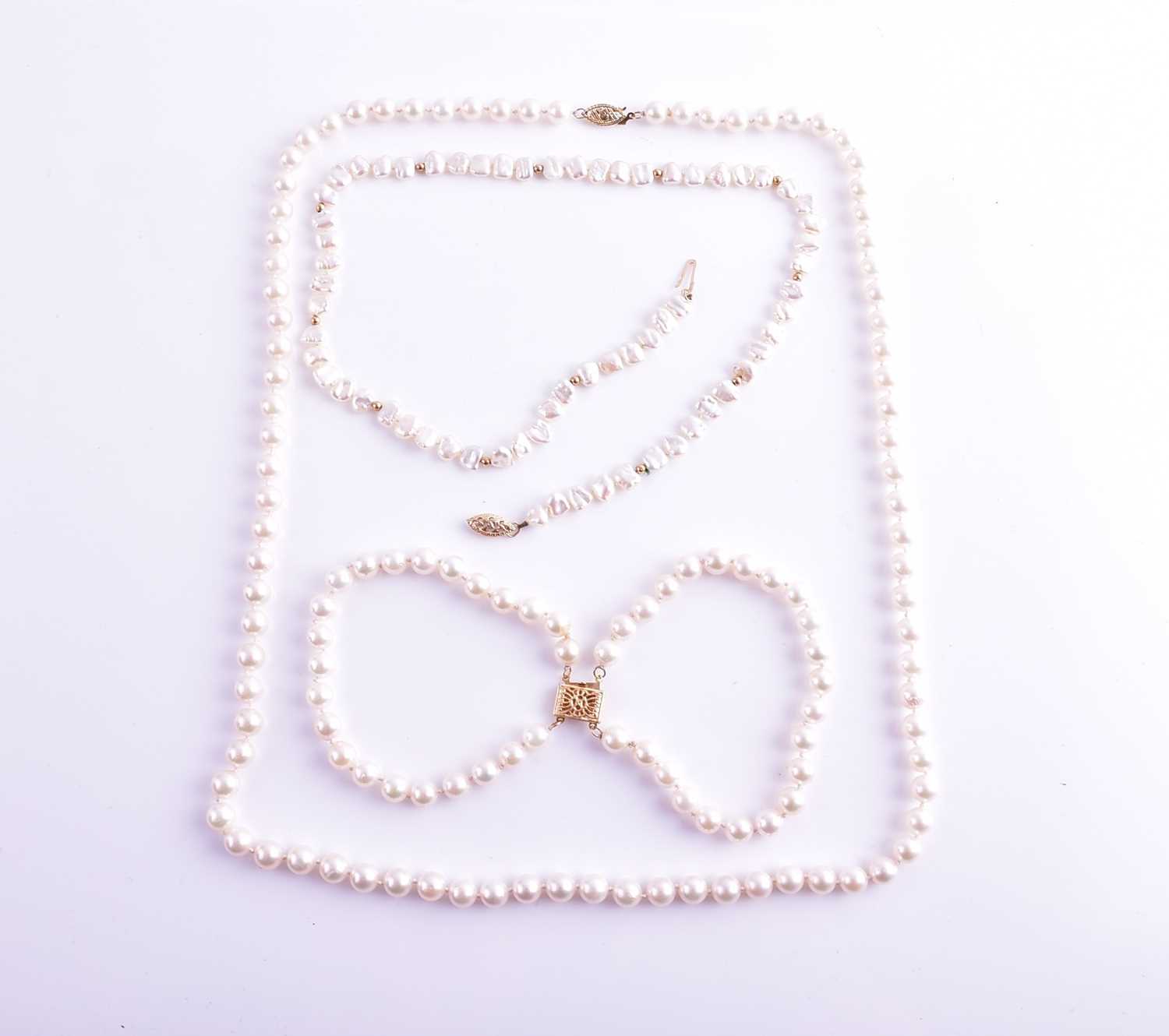 A cultured pearl necklace with yellow metal clasp, together with a similar cultured pearl double