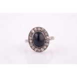An Edwardian style sapphire and diamond cluster ring, white metal set with a central oval cabochon