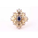 A sapphire and diamond openwork cluster ring; the large square plaque with central oval sapphire and