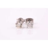 A pair of single stone diamond earrings; the round brilliant cut diamonds in simple four claw mounts