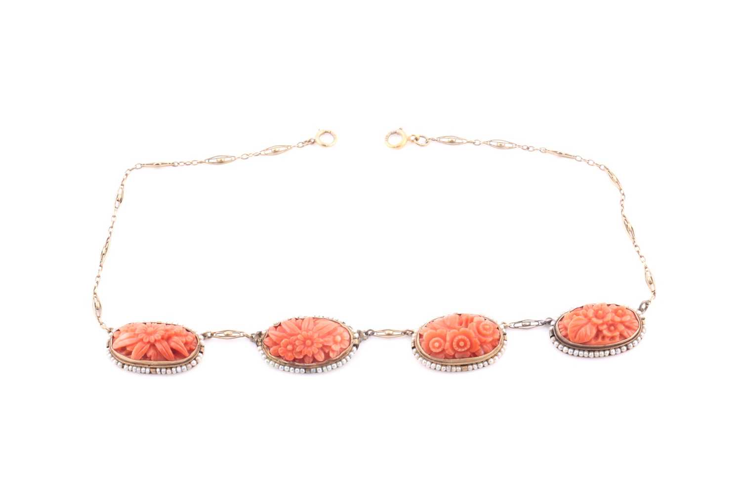 A late 19th / early 20th century coral and seed pearl necklace, set with four carved coral