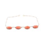 A late 19th / early 20th century coral and seed pearl necklace, set with four carved coral