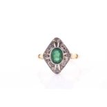 A yellow metal, diamond, and emerald ring, set with a mixed oval-cut emerald, bezel-set within an