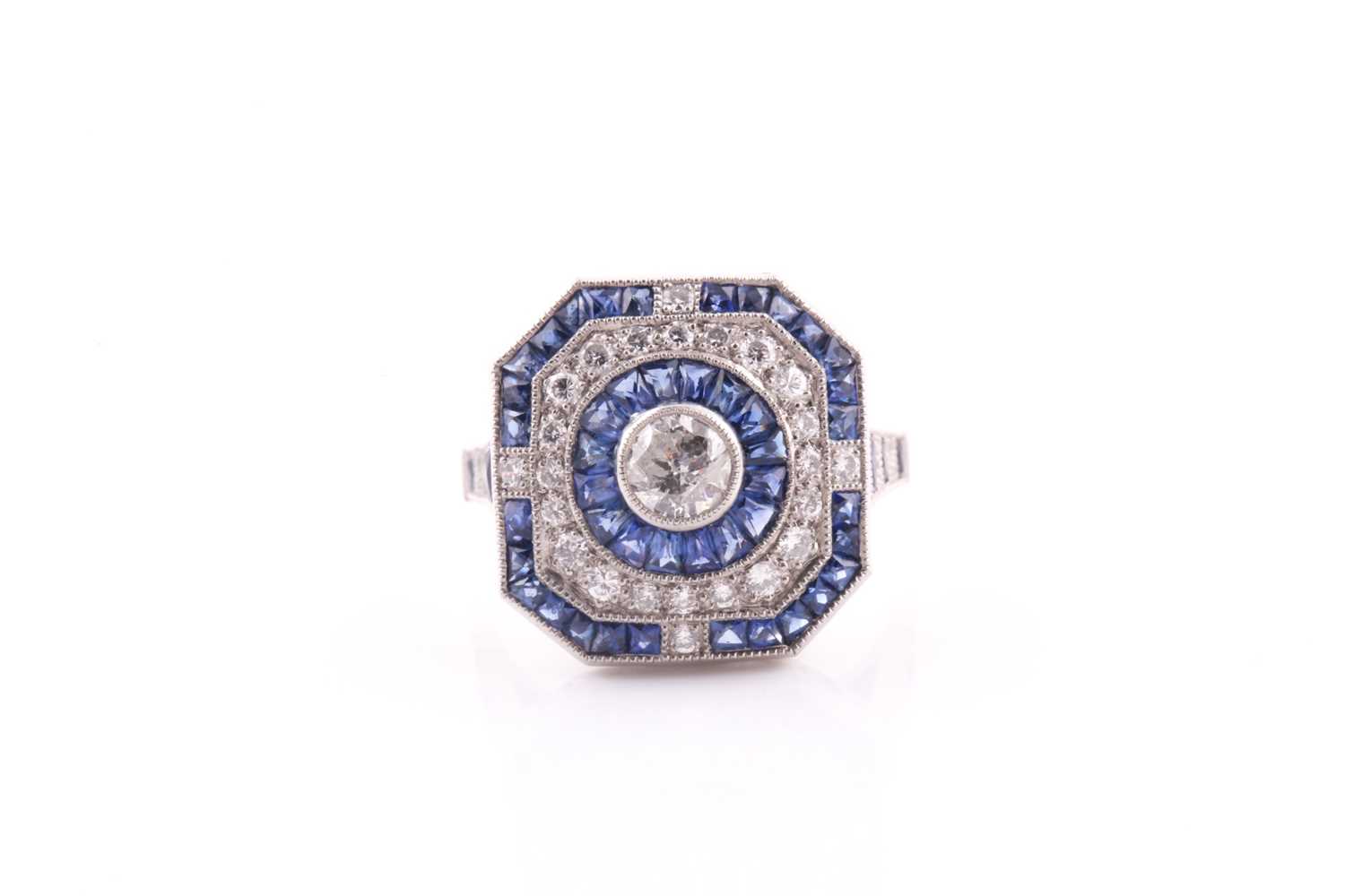 A platinum, diamond, and sapphire cluster ring, centred with a round-cut diamond within a