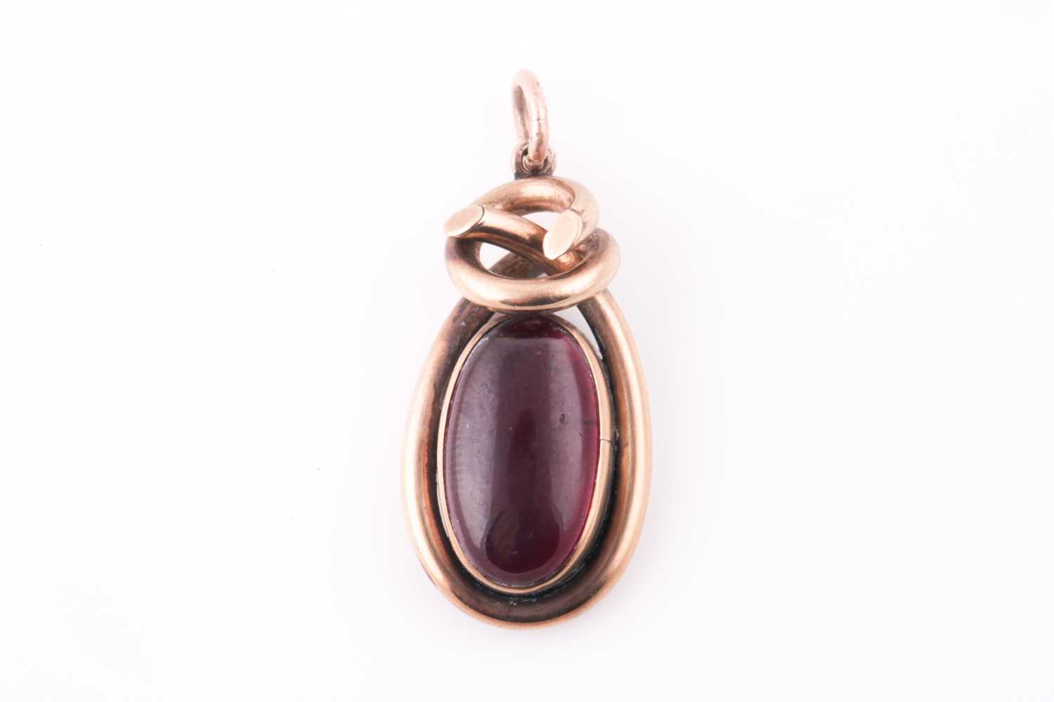 A Victorian yellow metal pendant, the twisted mount set with a cabouchon garnet, with vacant glass