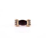 A 14k yellow gold, garnet, and black diamond ring, set east to west with a mixed fancy-cut garnet,