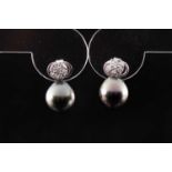 A pair of black South Sea pearl and diamond earrings, each with a floral diamond cluster above a