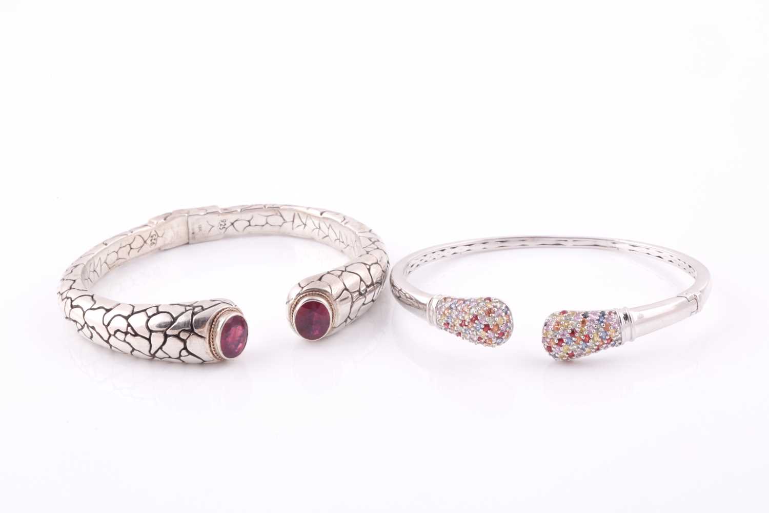 A silver torque bangle, with a mixed oval-cut ruby set to each terminal within a rope-twist yellow